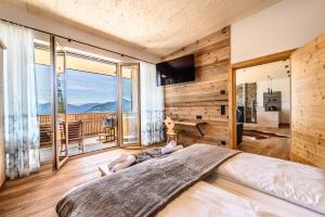 a woman laying on a bed in a bedroom with a large window at Das Eulersberg Apartments & Chalets in Werfenweng