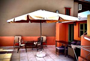 eine Terrasse mit einem Sonnenschirm, Tischen und Stühlen in der Unterkunft Casa Mersini in Chania