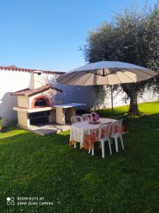 uma mesa com um guarda-chuva em frente a uma casa em La Chicca 4/6 posti letto em Capannori