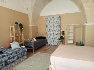 a bedroom with a bed and a couch and a window at Casina Al Maestrale in San Pancrazio Salentino