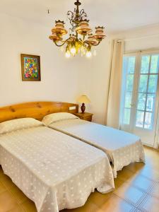 1 dormitorio con 1 cama blanca grande con lámpara de araña en Trill Brisas Kim casa Estartit Rocamaura, en Torroella de Montgrí