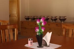 un jarrón negro con flores rosas sobre una mesa en Ldazes Camp en Hundar