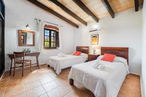 a bedroom with two beds and a table and a desk at Coster Puig in Pollença +16 photos