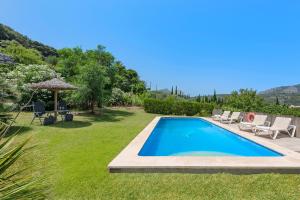 a swimming pool in a yard with chairs and an umbrella at Coster Puig in Pollença