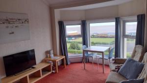 a living room with a tv and a couch and a table at The Kathrene Second Floor Sea View in Fleetwood