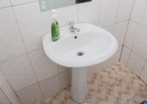 een witte wastafel in een wit betegelde badkamer bij Cool 1 B/Room Thika Road in Nairobi