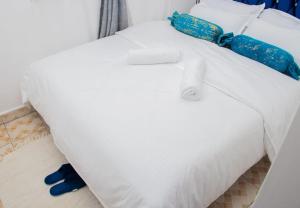 Una cama blanca con corbatas azules encima. en Cool 1 B/Room Thika Road en Nairobi