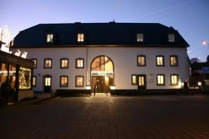a large white building with lit windows at night at POSTRELAIS ARDENNES "Beau Séjour" in Burg-Reuland