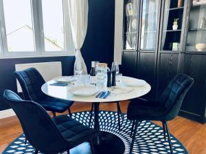 une salle à manger avec une table et des chaises blanches dans l'établissement "Le Theodore" Appartement charmant proche gare avec place de parking devant, quartier très calme, by PRIMO C0NCIERGERIE, à Nevers