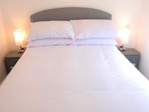 ein Bett mit weißer Bettwäsche und Kissen sowie zwei Lampen in der Unterkunft Chez Ana in Saxmundham