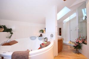 Baño blanco con bañera y lavamanos en Landhotel Alphorn en Ofterschwang