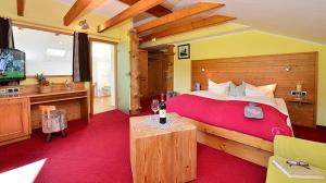 een slaapkamer met een groot bed en een flatscreen-tv bij Landhotel Alphorn in Ofterschwang