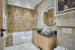 uma casa de banho com um lavatório, uma banheira e um espelho. em Appartement Coeur Montmartre by Studio prestige em Paris