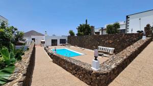 a stone wall with a swimming pool in front of a building at Villa Estrella Polar in Tahiche
