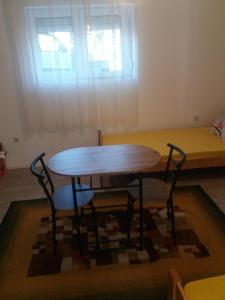 uma mesa de madeira e duas cadeiras num quarto em Kursumlija em Kuršumlija