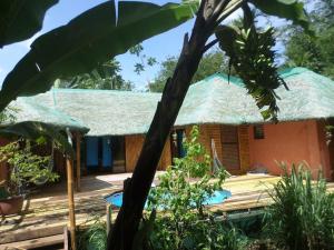 une maison au toit de chaume avec une piscine dans l'établissement Maison en bambou, éco lodge, à Pila