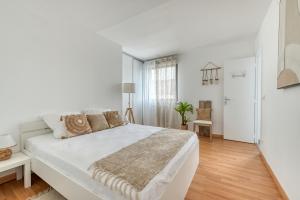 um quarto branco com uma grande cama branca e pisos em madeira em Duplex with terrace and parking in Villejuif em Villejuif