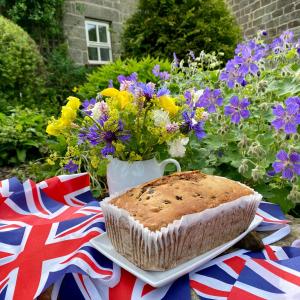 a cake on a plate next to a vase of flowers at Grove House Levisham in Pickering