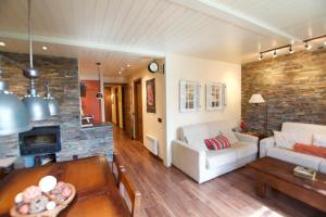 ein Wohnzimmer mit einem weißen Sofa und einer Ziegelwand in der Unterkunft Apartamento con jardín - Montana Park in Enveitg