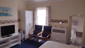 a living room with two chairs and a television at The Kathrene Holiday Flats in Fleetwood