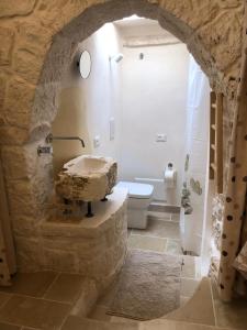 a bathroom with a toilet and a stone wall at Trullo del Sol in Ceglie Messapica