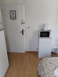 a room with a kitchen with a microwave and a door at Studio Saint-Jacques in Paris