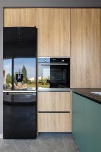 una cocina con horno negro y armarios de madera en SUMMER PEARLS LUXURY VILLAS en Polykhrono