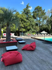 deux sacs de couchage rouges sur une terrasse à côté d'une piscine dans l'établissement Mercure Bordeaux Lac, à Bordeaux