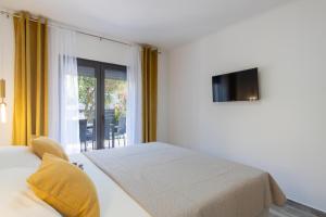 a white bedroom with a bed and a window at Apartmani PARDON in Pag