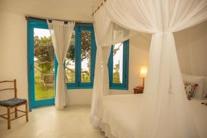 a bedroom with a bed with white curtains and a window at Caraiva Bela Vista in Caraíva