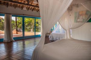 a bedroom with a bed with white curtains at Caraiva Bela Vista in Caraíva