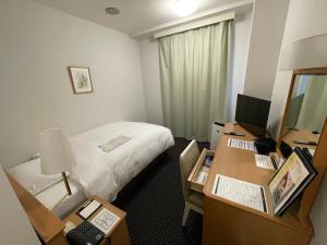 Habitación de hotel con cama y escritorio con ordenador en Grand Park Hotel Panex Iwaki en Iwaki