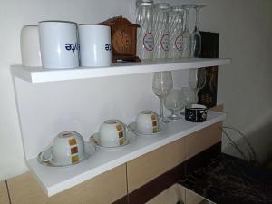 a shelf with cups and plates and wine glasses at Arad Apartment - Cozy Vintage new in Arad