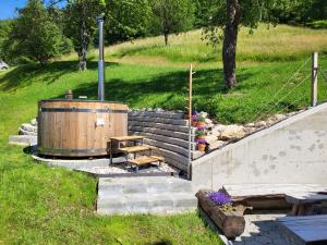 Jurček Holiday Home في Kotlje: حوض استحمام ساخن خشبي ومقاعد خشبية في ساحة