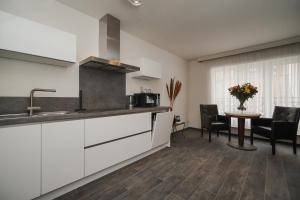 una cucina con lavandino e tavolo con sedie di Aparthotel Yvonne a Ostenda