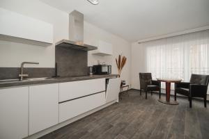 a kitchen with white cabinets and a table and chairs at Villa Yvonne in Ostend