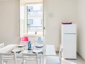 a white dining room with a table and a refrigerator at Homiday - BordoPineta Centro in Pineto