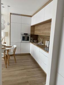 eine Küche mit weißen Schränken und einem Tisch mit Stühlen in der Unterkunft Apartament NADMORSKI z Basenem Klifowa Rewal in Rewal