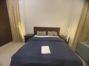a bedroom with a blue bed with a white towel on it at Beautiful Furnished Studio Building Apartment 903 AL Nahyan in Abu Dhabi