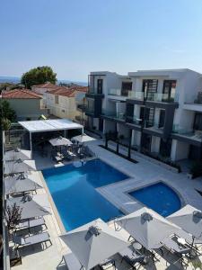 a swimming pool with umbrellas and chairs and buildings at Evion Residence A11 in Nikiti