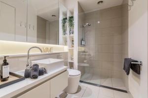 a white bathroom with a sink and a shower at Charming 1-Bedroom Heritage Apartment in Melbourne