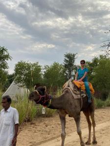 a woman riding on the back of a camel at Umaid Desert Camp, Raisar in Bikaner