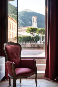 a red chair sitting in front of a window at Hotel San Marco in Gubbio