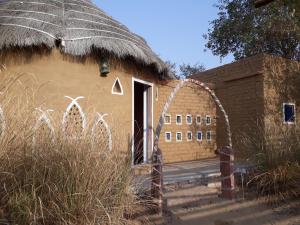 a building with a thatch roof and a door at Umaid Desert Camp, Raisar in Bikaner