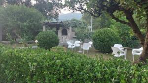 a group of white chairs and a table in a garden at Apartments Ivo Bozinovic in Tivat