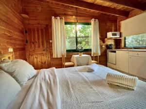 1 dormitorio con 1 cama blanca en una cabaña de madera en Adventure - חוויה, en Amirim