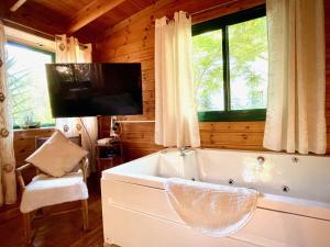uma grande banheira branca num quarto com uma televisão em Adventure - חוויה em Amirim