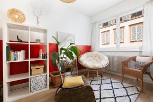 ストラスブールにあるLe Cocon - Proche Gare - Lumineux & Centre Ville - Commerces à Proximitéの赤い壁のリビングルーム(テーブル、椅子付)