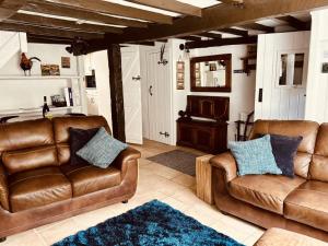 uma sala de estar com dois sofás de couro e um tapete em The Roost - Askrigg 18th Century Cottage em Askrigg