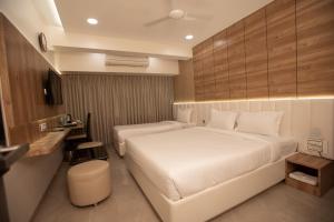 a hotel room with two beds and a desk at Hotel Naaz Executive in Mumbai